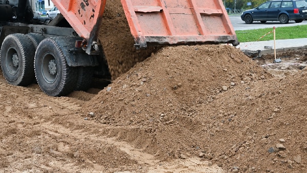 A bulldozer in action, skillfully moving heaps of finely screened dirt at a construction site for landscaping purposes.