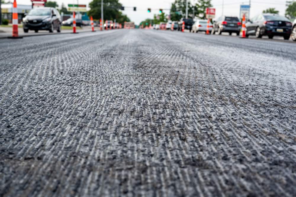 Close-up view of a new road under construction with a layer of Granular Subbase in Southern California, trucks working in the backdrop.