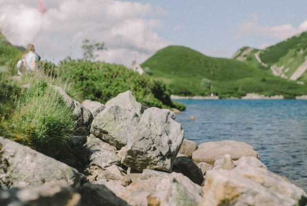 Commercial riprap lining a serene lakeside, showing large, irregular stones effectively preventing shoreline erosion.