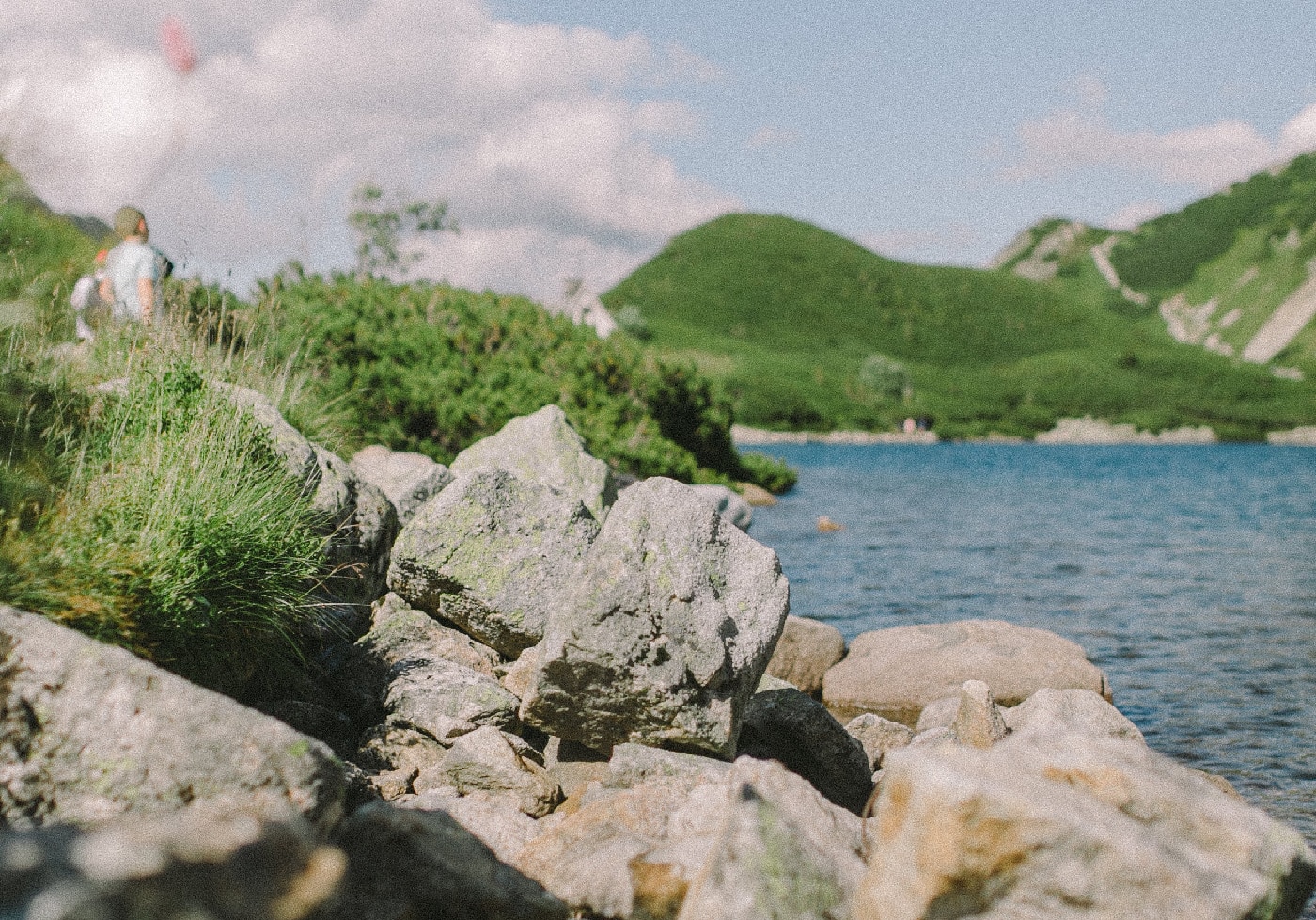 Commercial riprap lining a serene lakeside, showing large, irregular stones effectively preventing shoreline erosion.