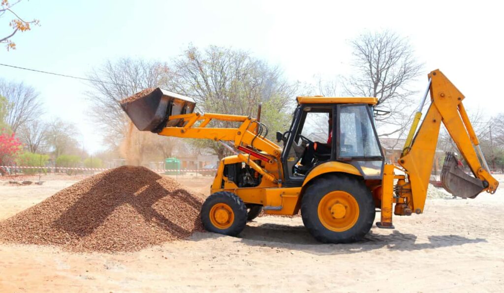 Excavator picking up a pile of screened dirt for site prep