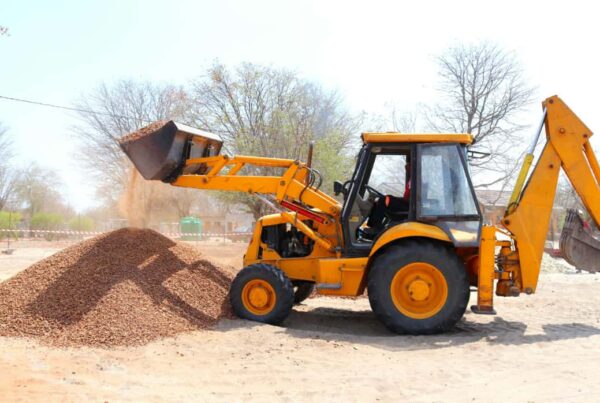 Excavator picking up a pile of screened dirt for site prep