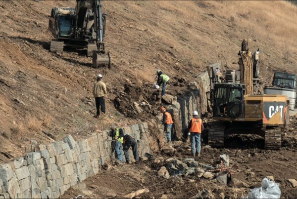 Construction workers install granite blocks along a slope, showcasing granite construction jobs.