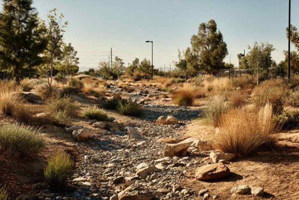 A dry landscape wash filled with drainage granite rock used for erosion control in arid climates.