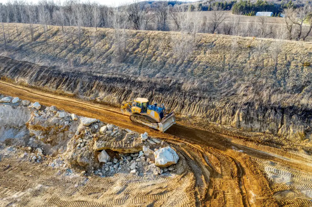 Road grader preparing a construction site for bulk rock delivery.